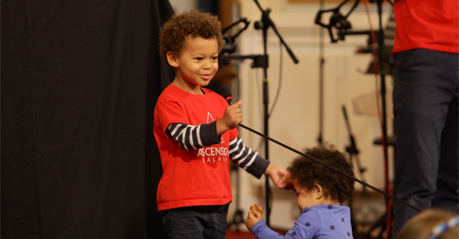 A toddler holding the microphone during Bubble Church